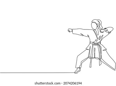 Continuous one line drawing young confident karateka woman in kimono practicing karate punch combat at dojo gym center. Mastering martial art sport concept. Single line draw design vector illustration