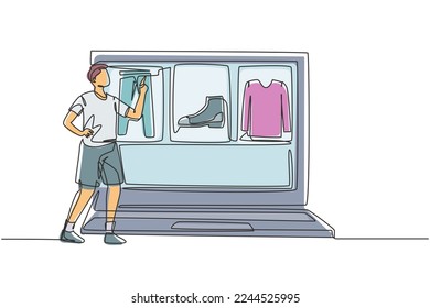 Continuous one line drawing young man choosing shopping items on a giant laptop screen. Sale, digital lifestyle with internet and gadgets concept. Single line draw design vector graphic illustration