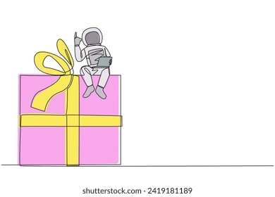Continuous one line drawing young energetic astronaut sitting on giant gift box holding laptop raise one hand. Awesome space gift. Cosmonaut outer space. Single line draw design vector illustration