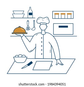 El cocinero se sienta en la mesa y sostiene el plato en la mano. Al fondo, un horno, latas y platos.