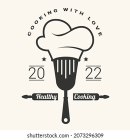 Cooking with love logotype with  spatula and chef hat. Healthy cooking. Vector illustration.