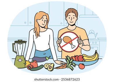 Cocinar un espectáculo vegano con un hombre y una mujer de pie en la cocina con verduras y demostrando un cartel de carne tachado. Chico y chica están preparando plato vegetariano, recomiendan dieta de alimentos saludables