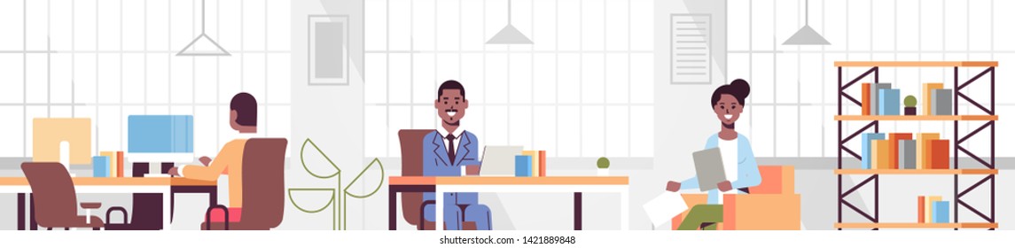 corporate staff employees working in creative co-working open space african american businesspeople sitting at workplace discussing new project modern office interior portrait horizontal