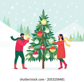 Couple Decorating Christmas Tree with Decorations Balls, Garland. Family Preparing for Celebration. Merry Christmas and Happy New Year. People Celebrate Winter Holidays. Man hanging toys on fir