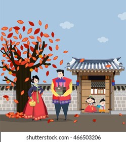 A couple dressed in Korean traditional costume having gifts for the national holiday and
 Korean style house behind. 