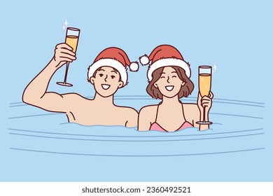 Couple drinks champagne sitting in hot tub on christmas eve and enjoying romantic setting and festive mood. Cheerful man and woman celebrating new year or christmas in outdoor hot water font