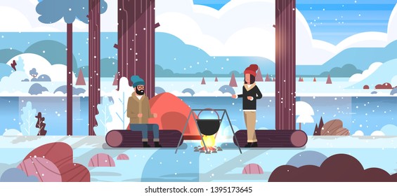 couple hikers man woman cooking meals in bowler boiling pot at campfire near camp tent camping concept winter landscape nature river mountains snowfall background horizontal full length