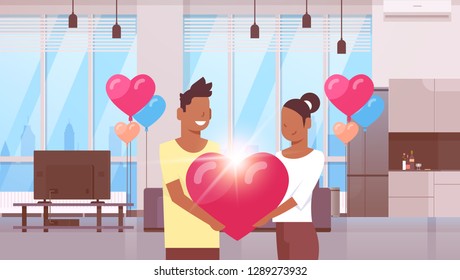 couple holding pink heart shape happy valentines day concept african american man woman lovers standing together modern apartment interior colorful air balloons flat horizontal