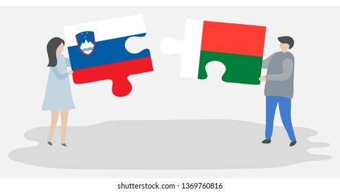 Couple holding two puzzles pieces with Slovenian and Malagasy flags. Slovenia and Madagascar national symbols together.