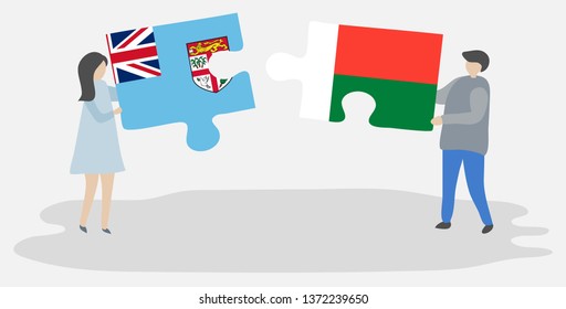 Couple holding two puzzles pieces with Fijian and Malagasy flags. Fiji and Madagascar national symbols together.