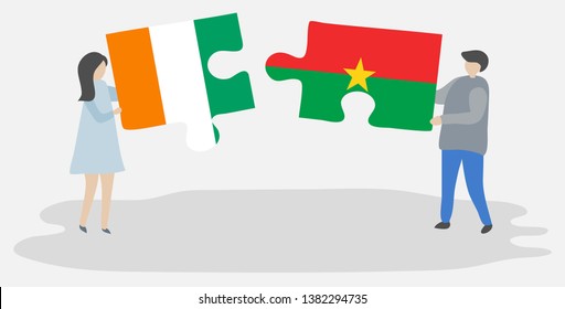 Couple holding two puzzles pieces with Ivorian and Burkinabe flags. Ivory Coast and Burkina Faso national symbols together.