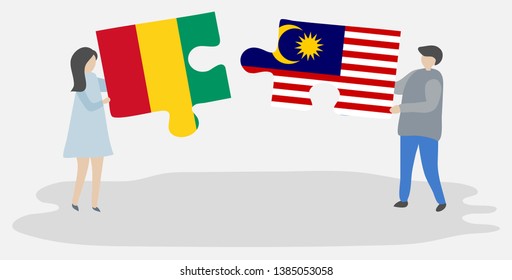 Couple holding two puzzles pieces with Guinean and Malaysian flags. Guinea and Malaysia national symbols together.