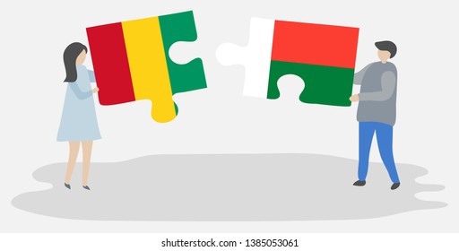 Couple holding two puzzles pieces with Guinean and Malagasy flags. Guinea and Madagascar national symbols together.