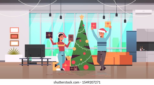 couple holding wrapped gift present boxes merry christmas happy new year holiday celebration concept man woman wearing santa hats modern living room interior flat full length horizontal vector