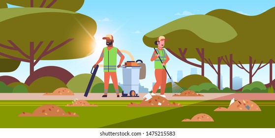 couple janitors gathering trash man using vacuum cleaner woman raking garbage cleaning service concept mix race cleaners working outdoor urban park landscape background full length horizontal