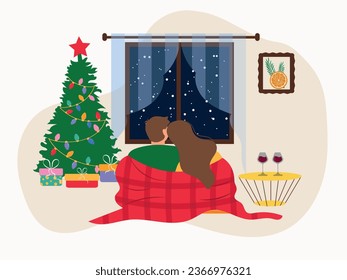 A couple in love in a blanket, looking out the window. The window next to the Christmas tree and gifts. A couple sits in an embrace and looks out the window, next to a coffee table with glasses of win