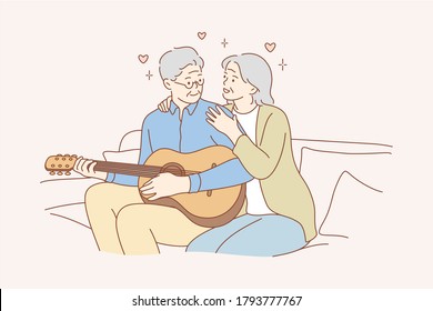 Couple, Love, Play, Romance, Music, Recreation Concept. Romantic Old Man And Woman Senior Citizens Pensioners Sitting On Couch Together And Playing Guitar Musical Instrument At Home. Happy Retirement.