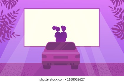 Couple in love watching movie sitting on car. Outdoor cinema