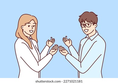 Couple of man and woman in business clothes make inviting gesture with hands. Guy and girl who created own startup are pointing back to inviting those who want to learn more about company