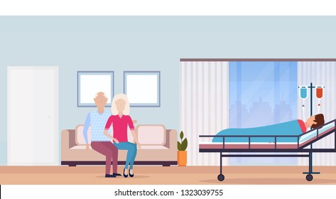 couple man woman visiting patient man lying in bed in intensive therapy ward, hospital room. interior modern medical clinic horizontal