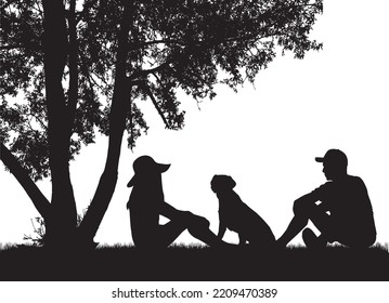 A couple of people with a dog are sitting under a tree.