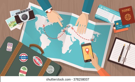 Couple planning a trip around the world, he is pointing on a map and she is using a mobile app, vacations and holidays concept