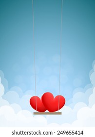 Couple of red hearts on swing in the daytime sky with clouds