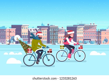 couple riding bike with fir tree gift box over city street buildings cityscape background merry christmas new year concept flat horizontal vector illustration