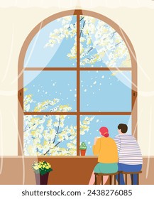 Una pareja sentada junto a la ventana del café y mirando los árboles amarillos con flores en primavera