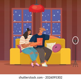 Couple sitting on sofa, broadcasting live, podcasting using phone. Man and woman record video, online podcast. People smiling at camera on smartphone. Bloggers filming video blog in apartment