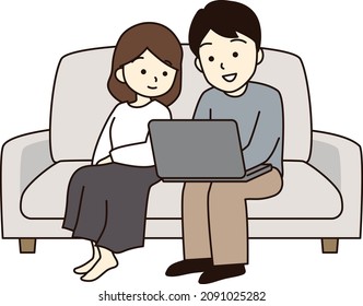 A couple sitting on the sofa and looking at a laptop.