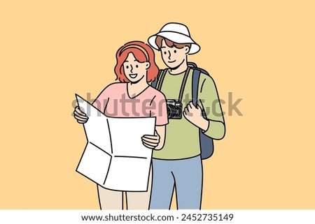 Couple of tourists study map, choosing route for hike in mountains with wildlife or walk along city streets. Tourists with photo camera use paper map for navigation and orientation on terrain.