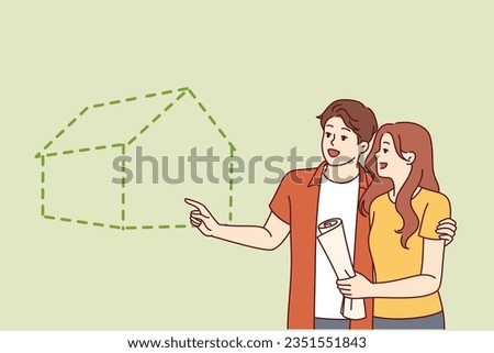 Couple visualizes buying new house with mortgage or renting large apartment in good neighborhood. Young happy man and woman smiling planning to build eco house for family life together