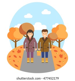 The couple is walking in autumn park. The nature is orange, red and yellow coloured. The autumn season.