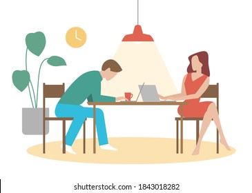 A couple working from home on their computers at the dining table with a bright light above them