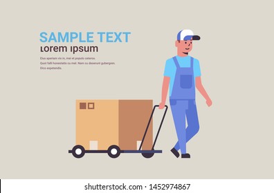 courier in uniform pushing trolley with cardboard box package mail express delivery service concept worker with hand truck flat full length horizontal copy space