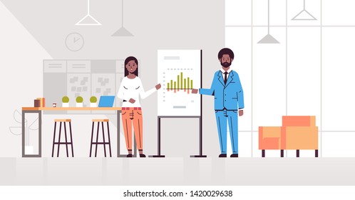 coworkers presenting financial graph on flip chart african american business couple at conference meeting making presentation concept modern office interior flat full length horizontal