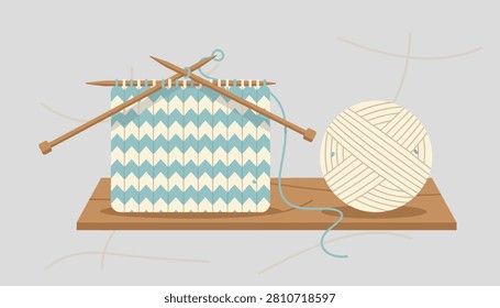 Cozy knitting project with wooden needles and blue striped fabric next to a big beige ball of yarn on a shelf.
