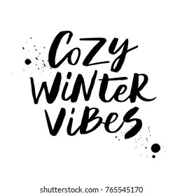 Cozy winter vibes - expressive hand lettering with splashes mascara. Isolated on white background. Print for t-shirt, mug, greeting cart and other. Vector illustration.