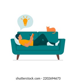 Creative man lying on the couch at home, he is reading and writing on a notebook, isolated on white background