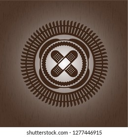crossed bandage plaster icon inside wooden emblem. Vintage.