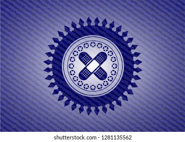 crossed bandage plaster icon inside badge with denim texture