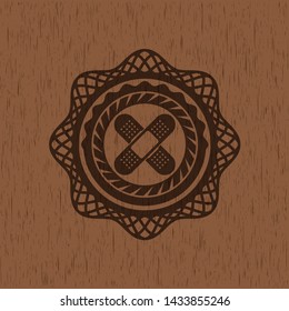 crossed bandage plaster icon inside wooden emblem. Vintage.