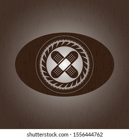 crossed bandage plaster icon inside realistic wood emblem