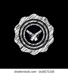 crossed pistols icon inside chalk emblem written on a blackboard