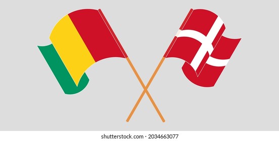 Crossed and waving flags of Guinea and Denmark
