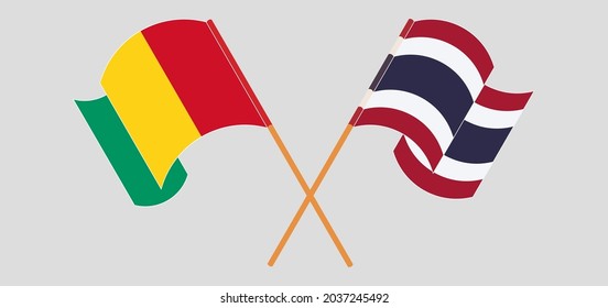 Crossed and waving flags of Guinea and Thailand