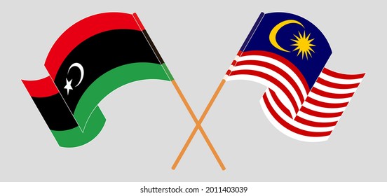 Crossed and waving flags of Libya and Malaysia