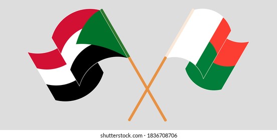Crossed and waving flags of Madagascar and Sudan