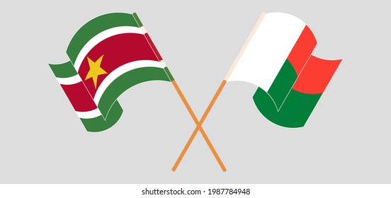 Crossed and waving flags of Suriname and Madagascar